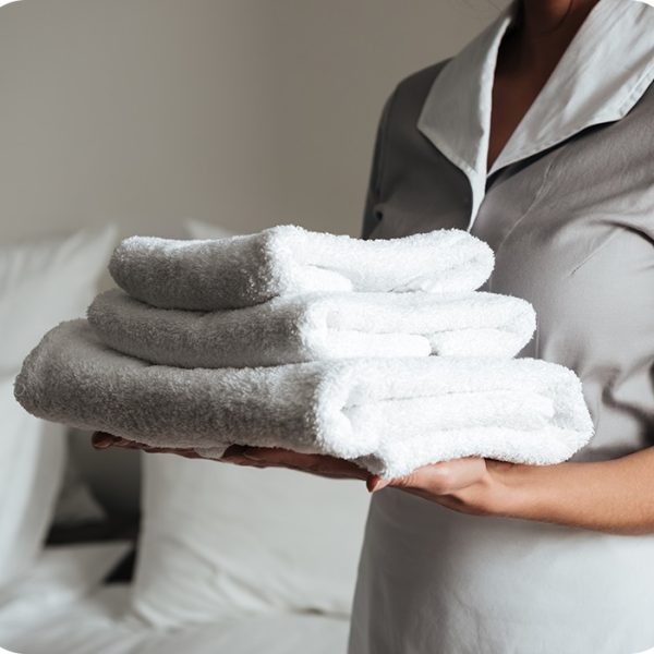 young-hotel-maid-standing-and-holding-fresh-clean-towels